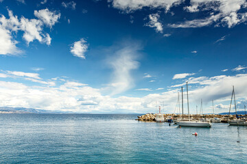 Boats and sailboats moored in the harbor of Opatija, Croatia on a sunny day with calm sea and blue...