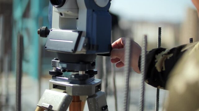 Surveyor using theodolite at construction site