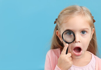 Surprised little girl with magnifying glass on light blue background. Space for text