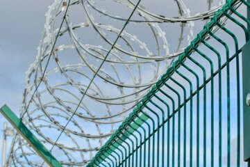 View of a prison fence topped with razor wire. Iron fence topped with barbed wire. Concept of...