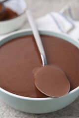 Liquid chocolate dough in bowl on grey table, closeup