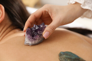 Woman undergoing crystal therapy to heal or restore her aura indoors, closeup
