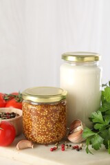Bottles of different tasty sauces and products on white table, closeup