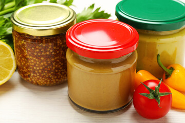 Bottles of different tasty sauces and products on white wooden table, closeup