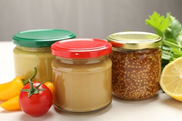 Bottles of different tasty sauces and products on white wooden table, closeup