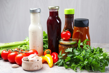 Bottles of different tasty sauces and products on grey table, closeup