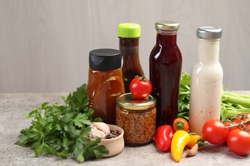 Bottles of different tasty sauces and products on grey table, closeup