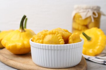 Fresh and pickled pattypan squashes on light grey table, closeup