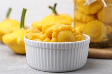 Fresh and pickled pattypan squashes on light grey table, closeup