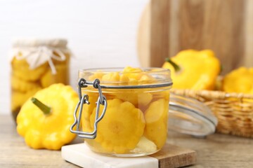 Fresh and pickled pattypan squashes on wooden table, closeup
