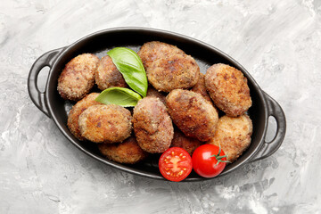Tasty meat patties with basil and tomatoes on grey textured table, top view