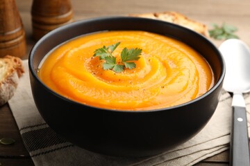 Tasty pumpkin cream soup with spices served on table, closeup