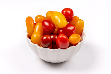 A white fluted dish of red and yellow mini grape or cherry tomatoes isolated on white