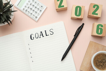 New Year. 2026 made of cubes and notebook with word Goals on pink table, top view