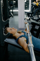 Young caucasian female bench pressing weights at gym: focus and strength