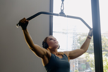 Young caucasian female exercising with lat pulldown machine in gym