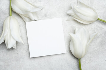 Wedding invitation square card mockup with copy space. white tulips flowers decor on grey