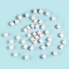 Scattered sugar cubes on light blue background in random pattern.
