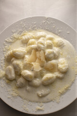 A delicious plate of gnocchi served in a rich creamy sauce, beautifully topped with grated parmesan cheese