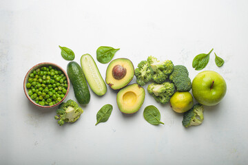 Fresh raw green vegetables and fruit white concrete background top view, diet, vegetarian food. Set of different green healthy products, clean eating nutrition