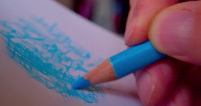 Close-up shot of hand drawing abstract pattern on paper with blue pencil