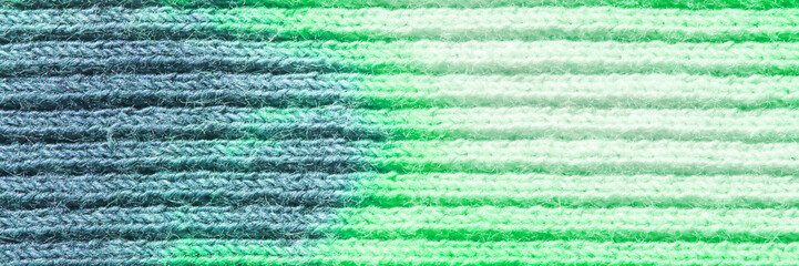 Close-up of textured green and blue yarn stripes in horizontal pattern.