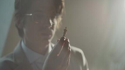 Chess player in a coat and eyeglasses focuses on the match at the tournament