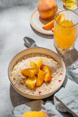 Oatmeal with peaches and nuts  in a bowl on a gray background with honey