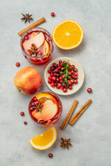 Flat lay of a cranberry drink in a glasses on a light background with cinnamon, berries and fruits.