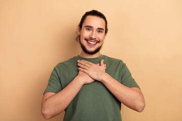 Smiling young man in green t shirt crosses his hands on chest in a warm friendly lifestyle portrait