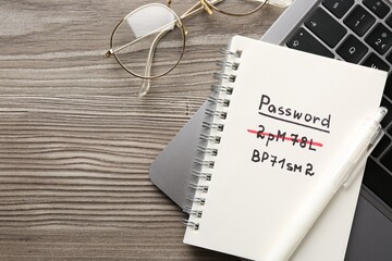 Changing password. Notebook with new and old passwords, laptop, pen and glasses on wooden table,...