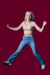 An Energetic Young Woman Joyfully Jumping Against a Vibrant Burgundy Background Canvas