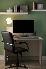 Stylish workplace with computer and grey mat on desk in office