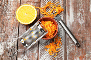 Orange zest, fresh fruit, zester tool and grater on wooden table, flat lay