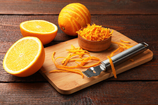 Orange zest, fresh fruits and zester tool on wooden table, closeup