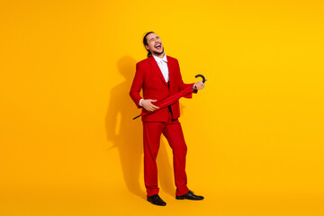 Funny stylish man in red suit laughs and twirls umbrella against bright yellow backdrop for bold fashion moment