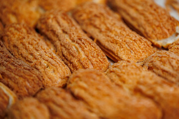 Closeup of freshly baked eclairs crispy pastries with textured golden crust in bakery factory