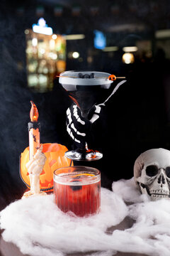 themed and decorated halloween drinks seen from above with morticia adams and negroni with eye ice skeleton hand in blurred pub