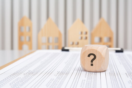 wooden cube with question mark on financial table with houses