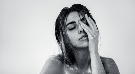 Studio close-up of a beautiful woman with natural makeup, wet hair, and sparkling glitter on her skin. 