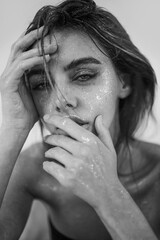 Studio close-up of a beautiful woman with natural makeup, wet hair, and sparkling glitter on her skin. perfect for beauty, skincare, fashion, or editorial concepts.