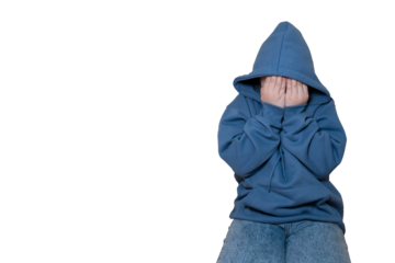 Upset or scared child in blue hoodie covering face with hands while sitting on transparent background with large space for text