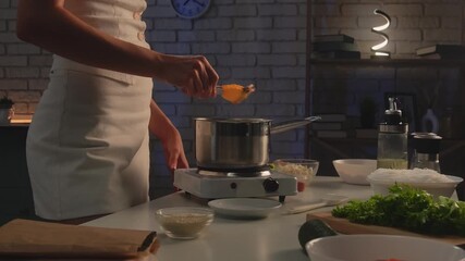 A woman prepares healthy food in her kitchen and takes boiled shrimp out of a saucepan. Ingredients and dishes are laid out on the table. Healthy eating, eco friendly products. - Powered by Adobe