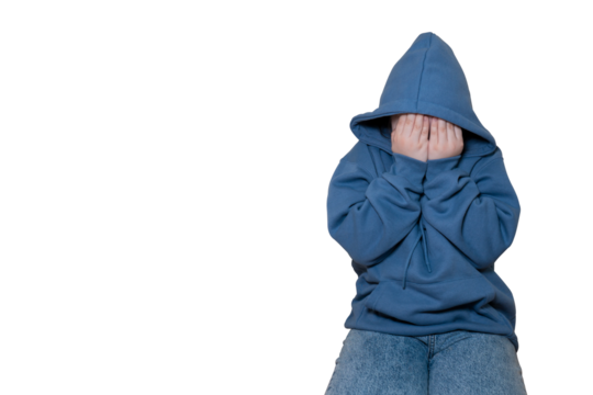Upset or scared child in blue hoodie covering face with hands while sitting on transparent background with large space for text