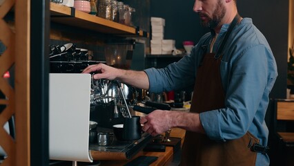 Caucasian waiter staff man guy employee making drink latte in cafe worker adding milk foam in cappuccino cafeteria barista using coffee machine catering small business male in apron serving customer