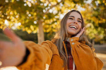 young attractive blond woman walking in autumn park, stylish , smiling, happy mood, taking selfie photo