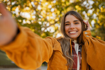 young attractive blond woman walking in autumn park, stylish , smiling, happy mood, taking selfie photo