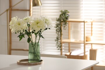 Beautiful chrysanthemum flowers in vase on white table indoors, space for text