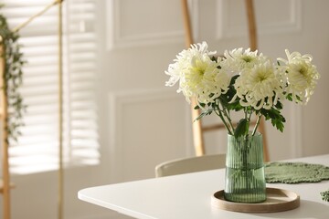 Beautiful chrysanthemum flowers in vase on white table indoors, space for text