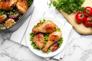 Grilled chicken drumsticks served with green peas on white marble table, flat lay